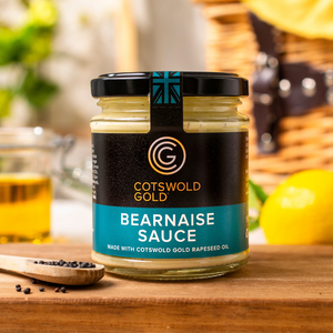 Jar of Cotswold Gold Bearnaise Sauce on a wooden board with ingredients in the background