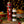 Two bottles of food products with decorative labels on a festive background with lights and food items.