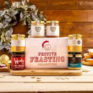 Cotswold Gold Festive Feasting Collection gift box featuring six gourmet condiments on a wooden board with decor.